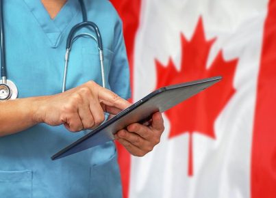 Surgeon or doctor using a digital tablet on the background of the Canada flag.